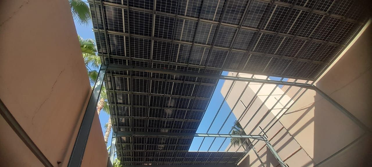Vue sous l'ombrière photovoltaïque : structure métallique et panneaux